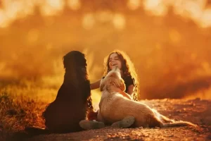 criança a brincar com dois cães
